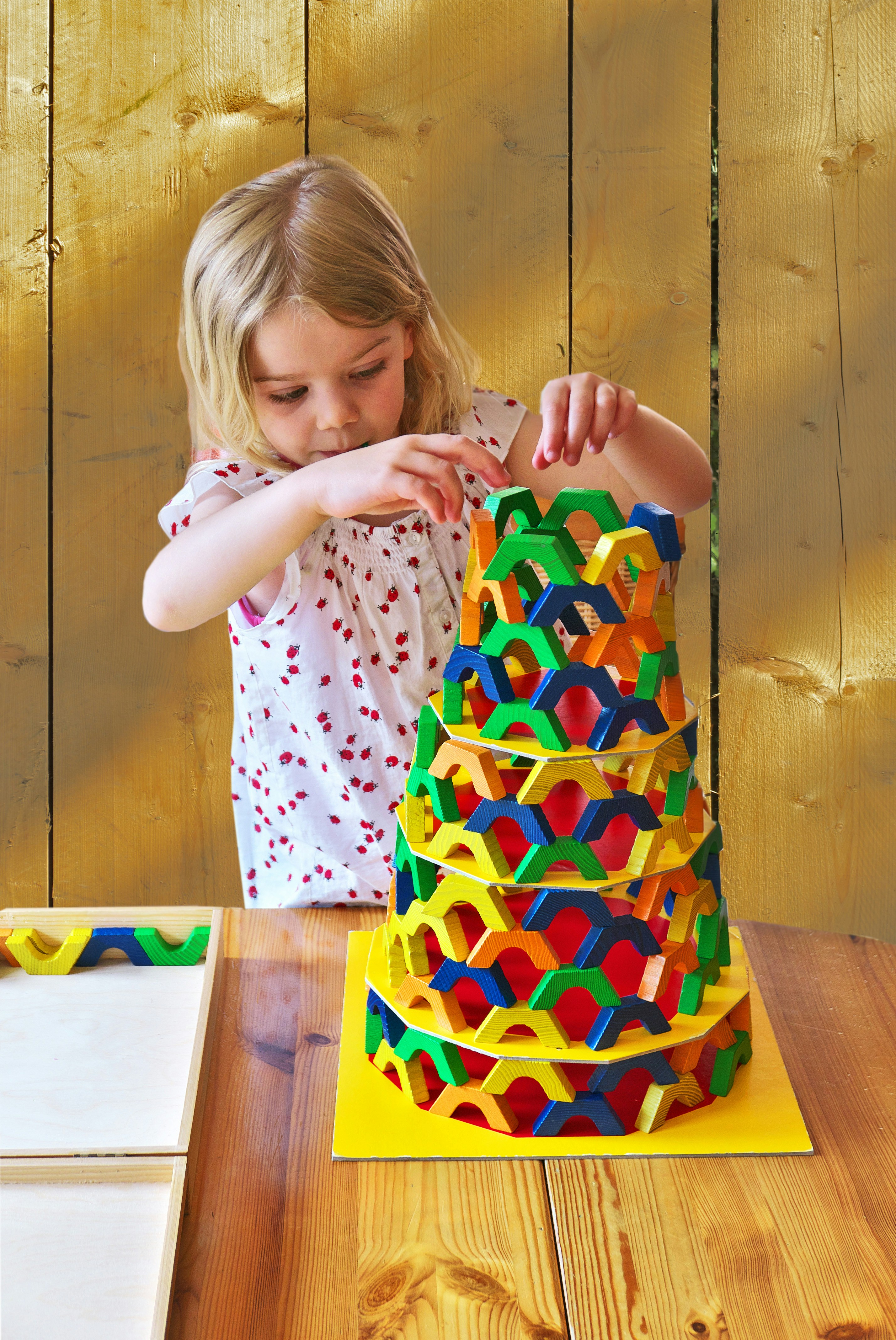 A child joyfully playing with colorful wooden building blocks, focused and engaged.